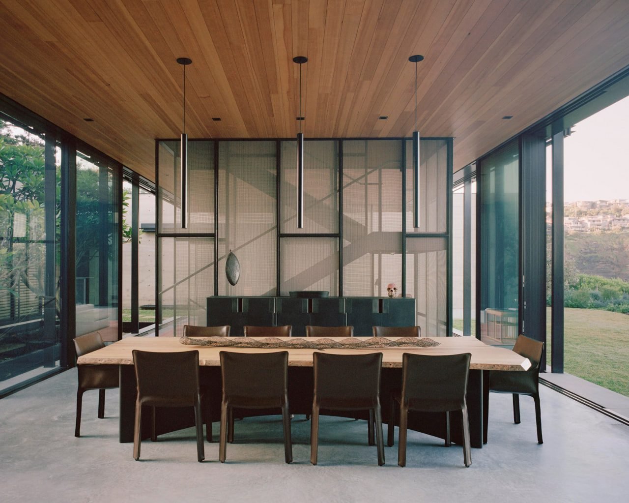 A tilt-and-turn window with a slim dark frame, sash tilted inward at the top, in a quiet minimal room